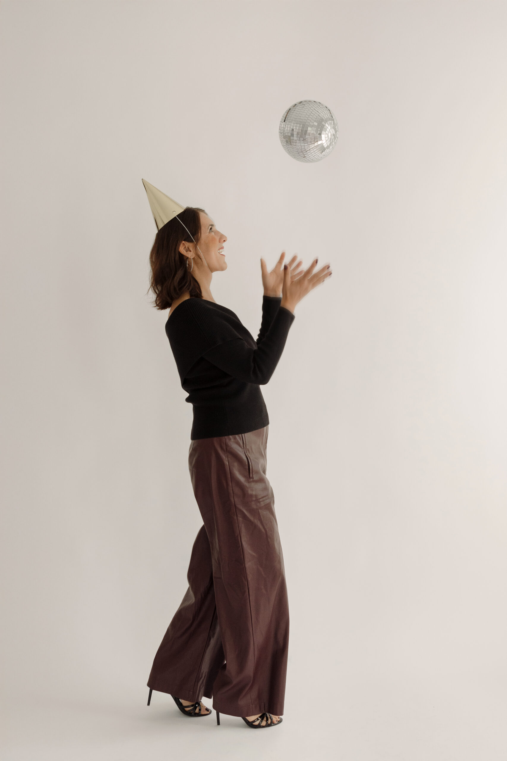Meg from Clapping Dog Media wearing a party hat and tossing a disco ball during her fun “Search Party” brand session.
